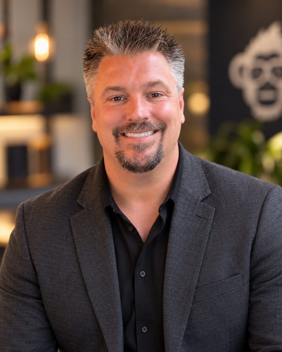 Kyle Gosselin in a dark blazer, with the Marketing Apes gorilla logo on the wall behind him